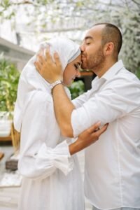 man and woman dressed in white, man kissing woman's forehead