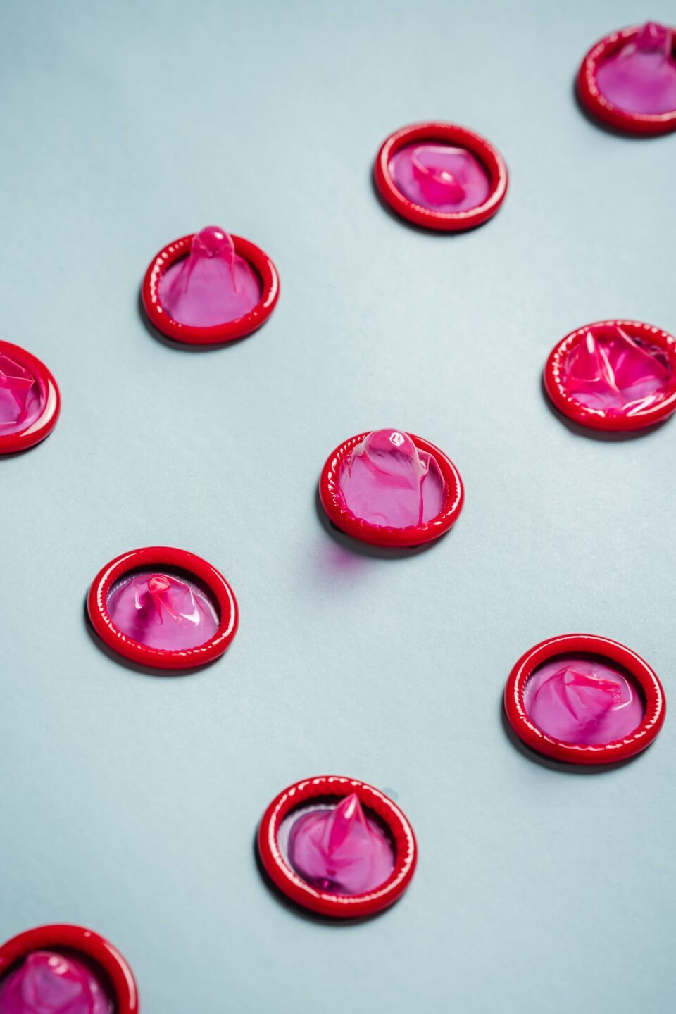 neatly lined up opened pink condoms
