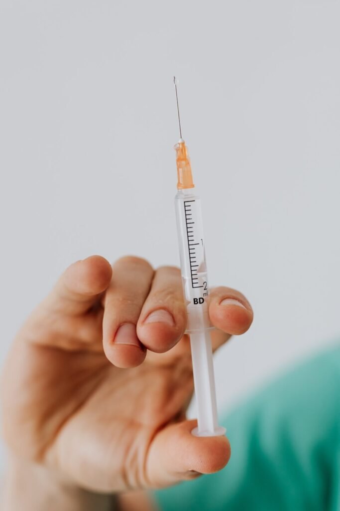 hand holding a medical needle and plunger, a shot